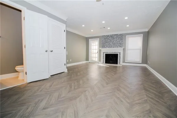 an empty room with wooden floor fireplace and windows