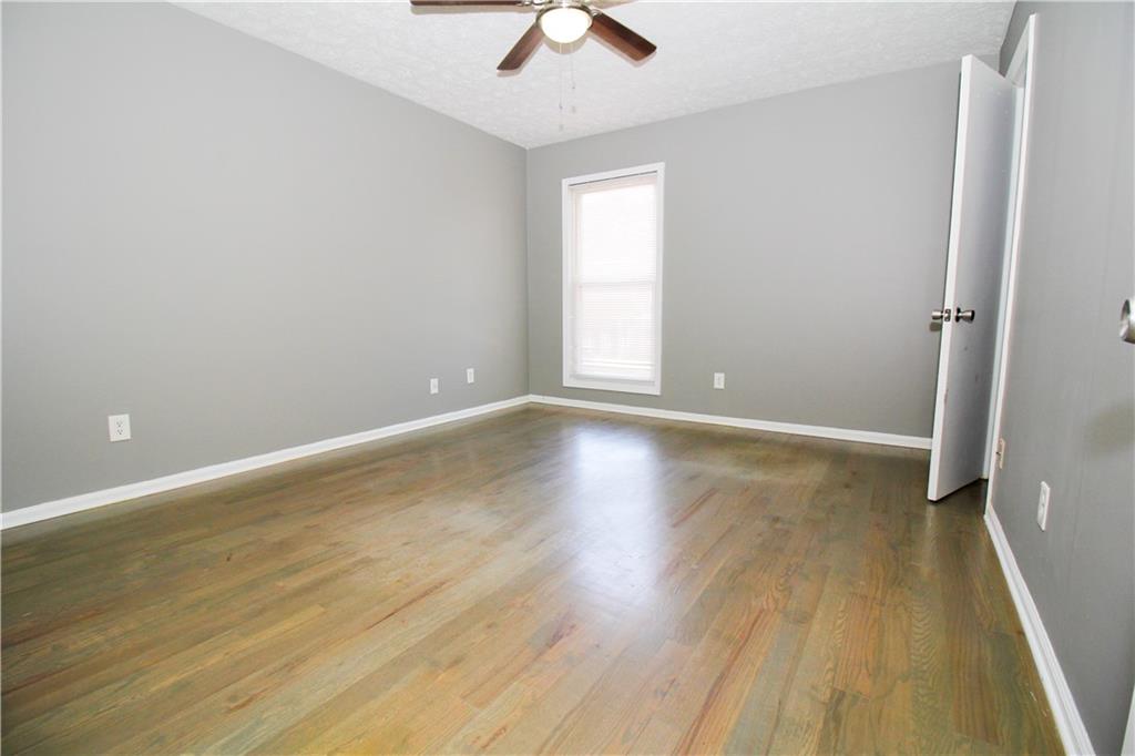2340 Beaver Ruin Road, Unit UN7 Norcross, GA 30071 - Photo 13 of 20 an empty room with wooden floor chandelier fan and windows