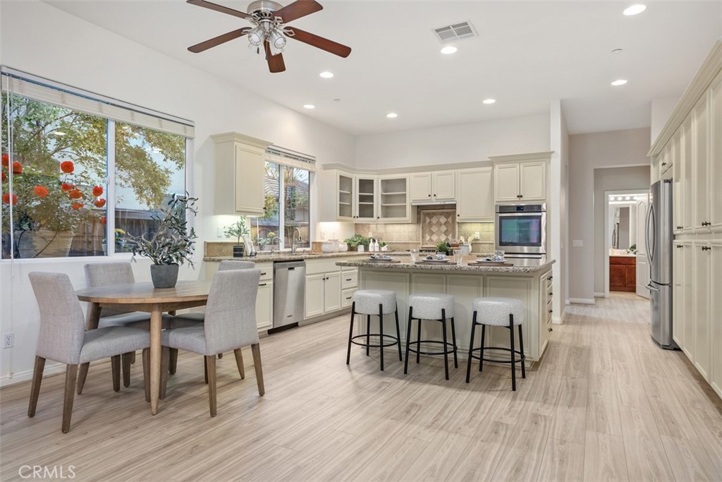 608 Inverlochy Drive Fallbrook, CA 92028 - Photo 20 of 52 a dining room with stainless steel appliances kitchen island granite countertop a table chairs and a refrigerator