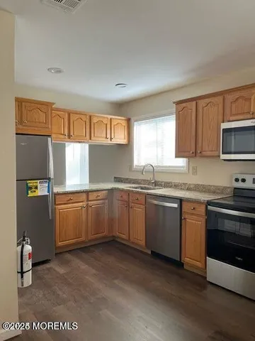 a kitchen with granite countertop a sink cabinets stainless steel appliances and a window