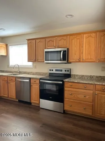 a kitchen with granite countertop a stove top oven microwave and cabinets