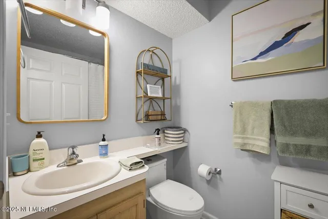 a bathroom with a granite countertop toilet a sink and mirror