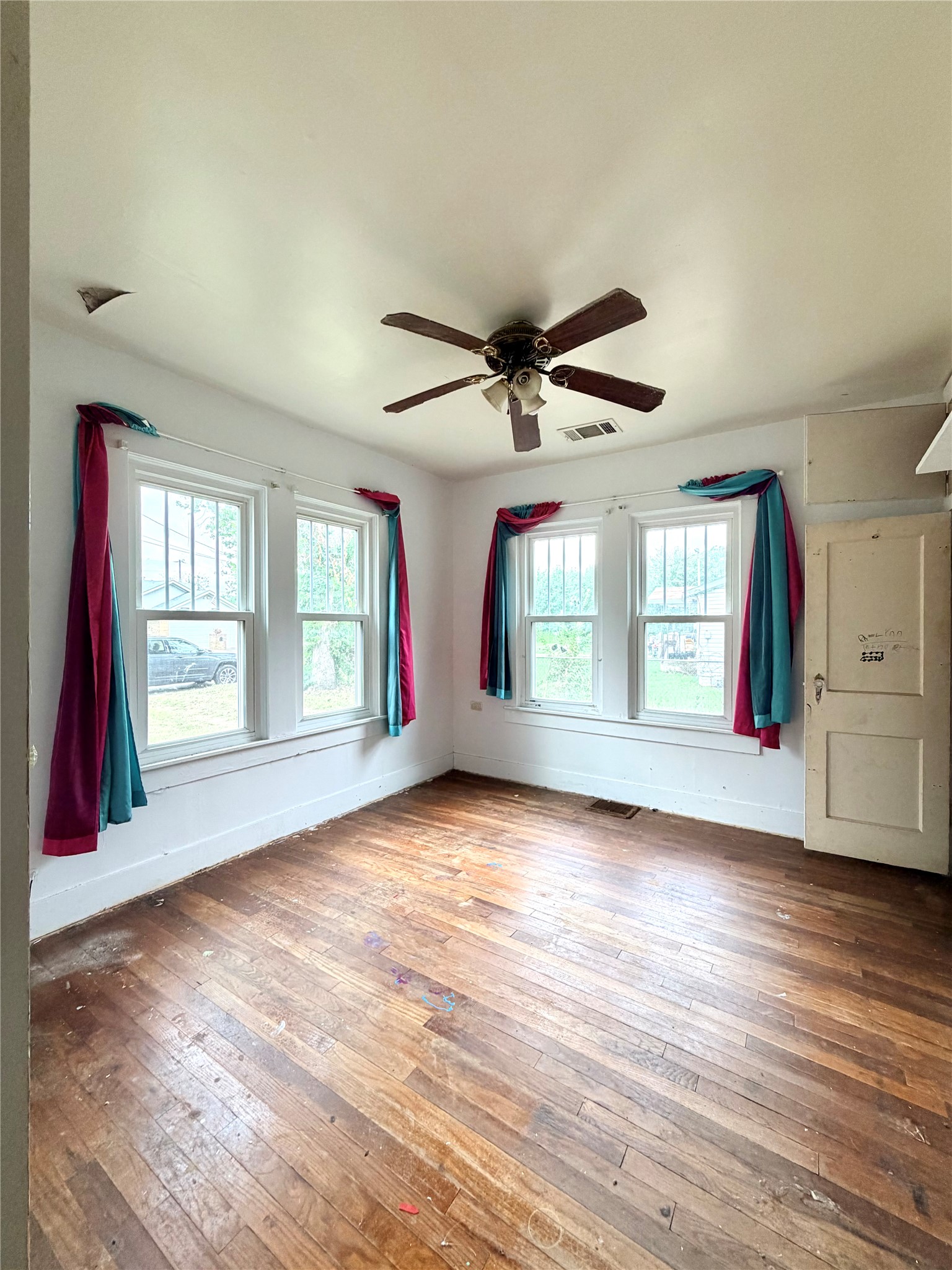 702 East 18th Street Cameron, TX 76520 - Photo 8 of 14 Sun-filled room awaits with classic hardwood floors and ample natural light through multiple windows.
