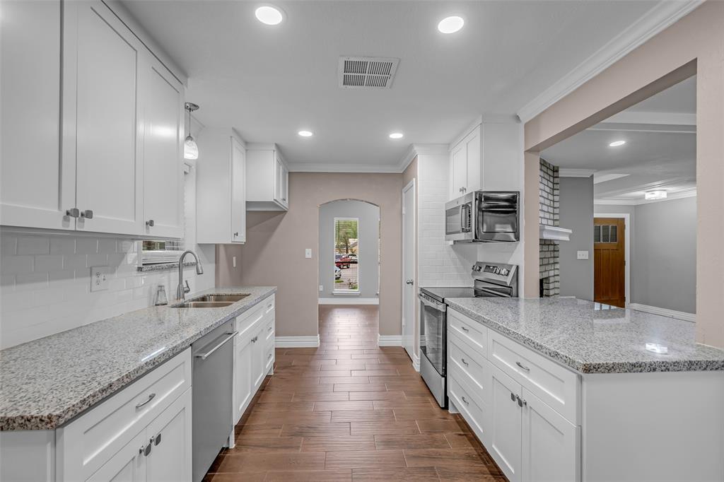 25703 Old Carriage Lane Spring, TX 77373 - Photo 12 of 25 The kitchen features white cabinetry, granite countertops, and stainless steel appliances