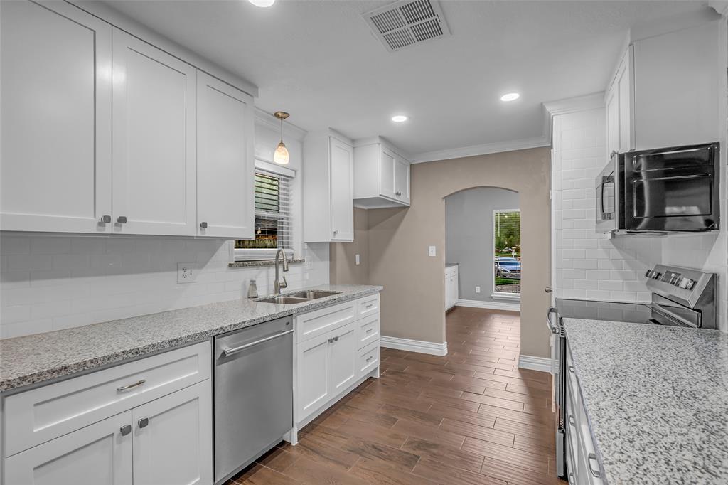 25703 Old Carriage Lane Spring, TX 77373 - Photo 14 of 25 The kitchen features white cabinetry, granite countertops, and a white subway tile backsplash
