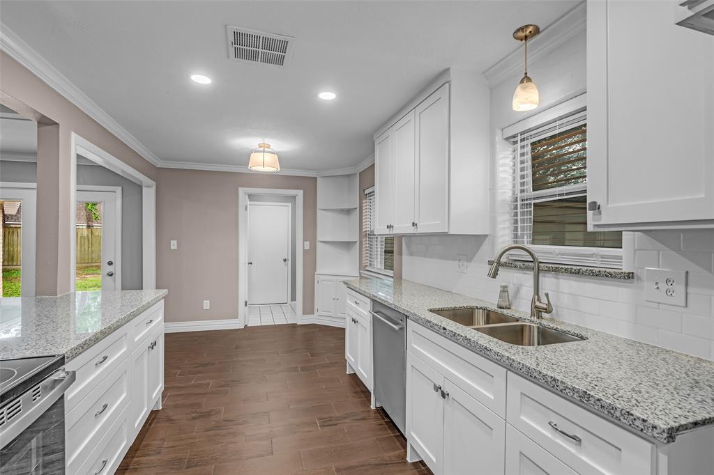 25703 Old Carriage Lane Spring, TX 77373 - Photo 15 of 25 The kitchen features white shaker style cabinetry, granite countertops, a double basin sink with a gooseneck faucet, and stainless steel appliances
