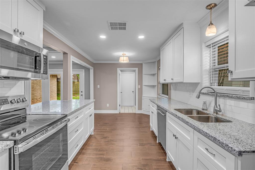 25703 Old Carriage Lane Spring, TX 77373 - Photo 16 of 25 The kitchen features white cabinetry, granite countertops, and stainless-steel microwave, oven, and dishwasher