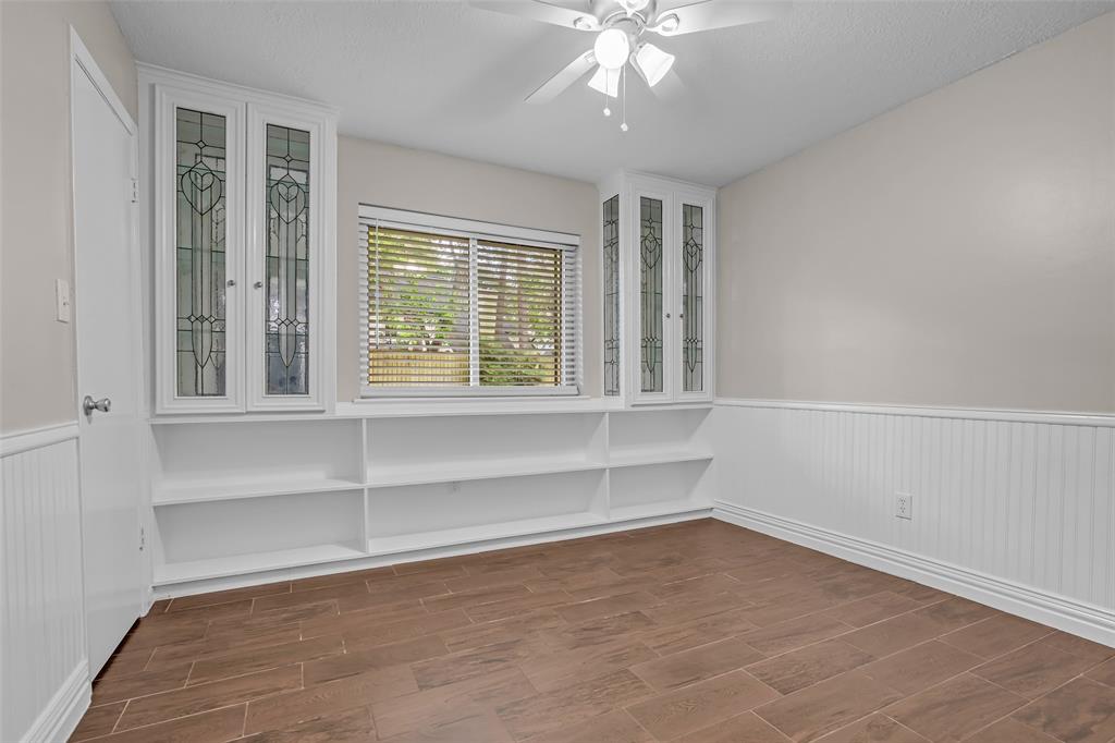 25703 Old Carriage Lane Spring, TX 77373 - Photo 21 of 25 This special room features wood-look tile flooring, wainscoting, and built-in shelving with decorative glass-front cabinets. Great for office or bedroom.