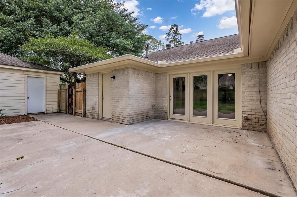 25703 Old Carriage Lane Spring, TX 77373 - Photo 23 of 25 The property features a spacious patio area with a white brick exterior and large glass doors. Perfect space for entertaining!