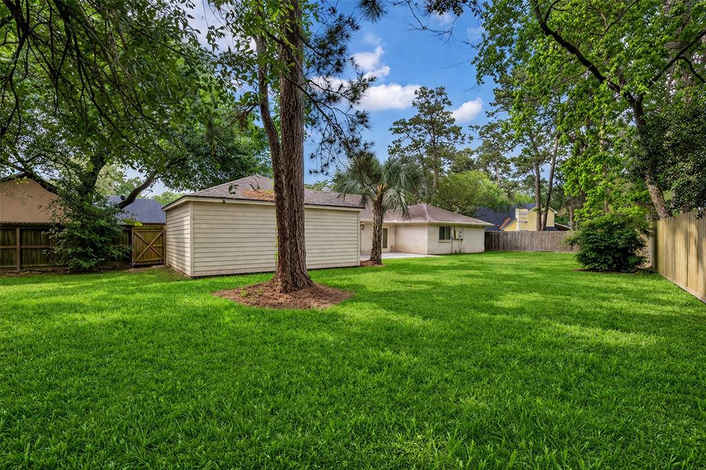 25703 Old Carriage Lane Spring, TX 77373 - Photo 24 of 25 The property features an expansive lawn with mature trees and a fenced yard