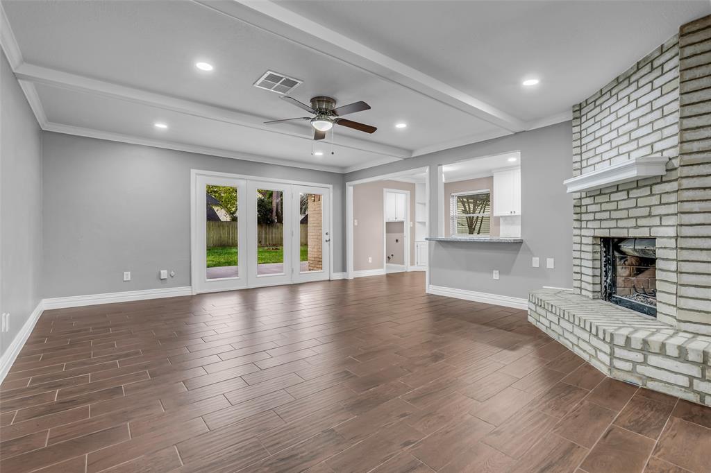 25703 Old Carriage Lane Spring, TX 77373 - Photo 6 of 25 Living area featuring wood-look tile flooring, a white brick fireplace, recessed lighting with access to back patio