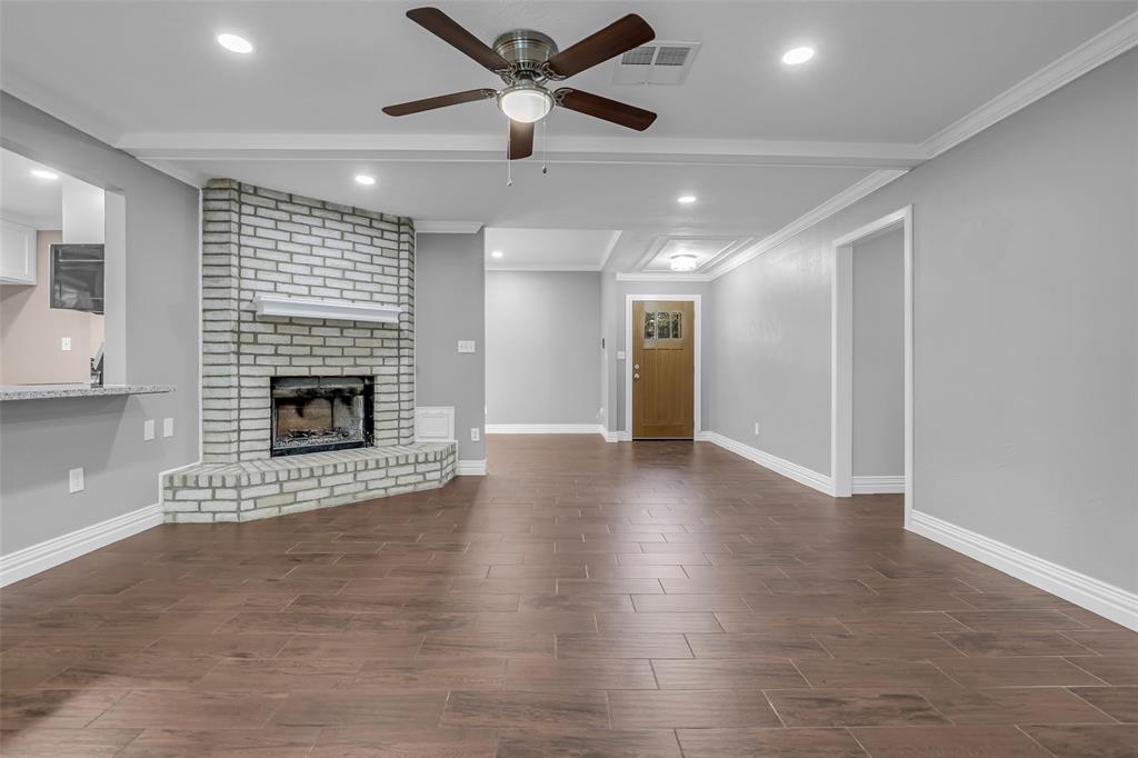 25703 Old Carriage Lane Spring, TX 77373 - Photo 9 of 25 Spacious living area featuring plank-style flooring, a brick fireplace with a mantel, and recessed lighting