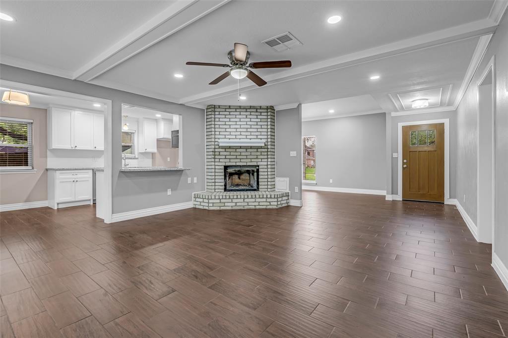 25703 Old Carriage Lane Spring, TX 77373 - Photo 10 of 25 Spacious living area featuring wood-look tile flooring, a brick fireplace, recessed lighting and open access to kitchen.