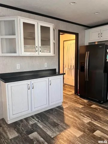 a view of a refrigerator in kitchen and an empty room