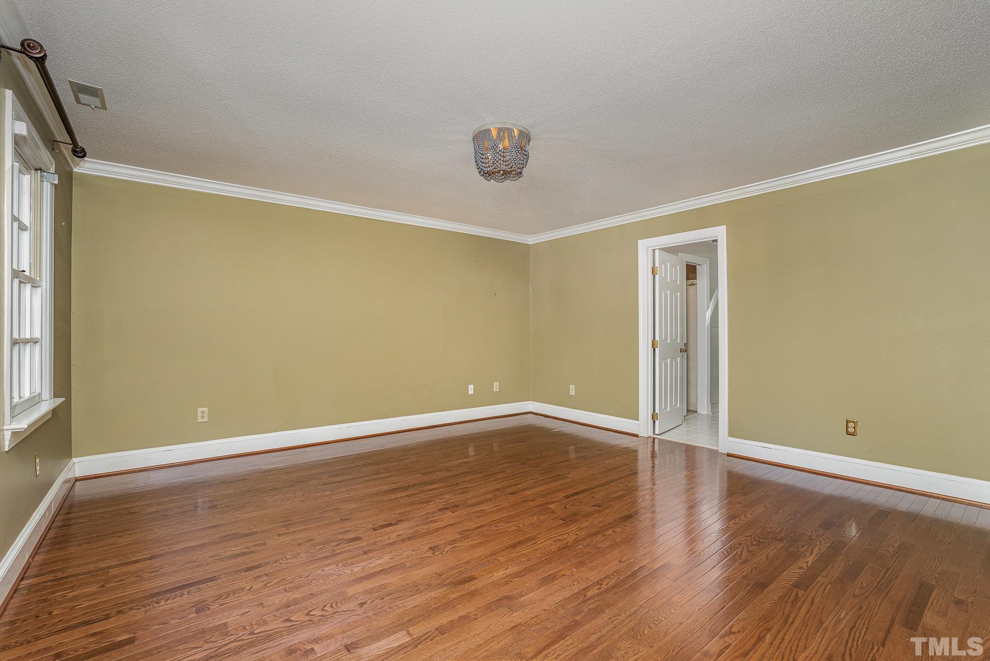 12036 Warwickshire Way Raleigh, NC 27613 - Photo 17 of 40 a view of an empty room with wooden floor and a window