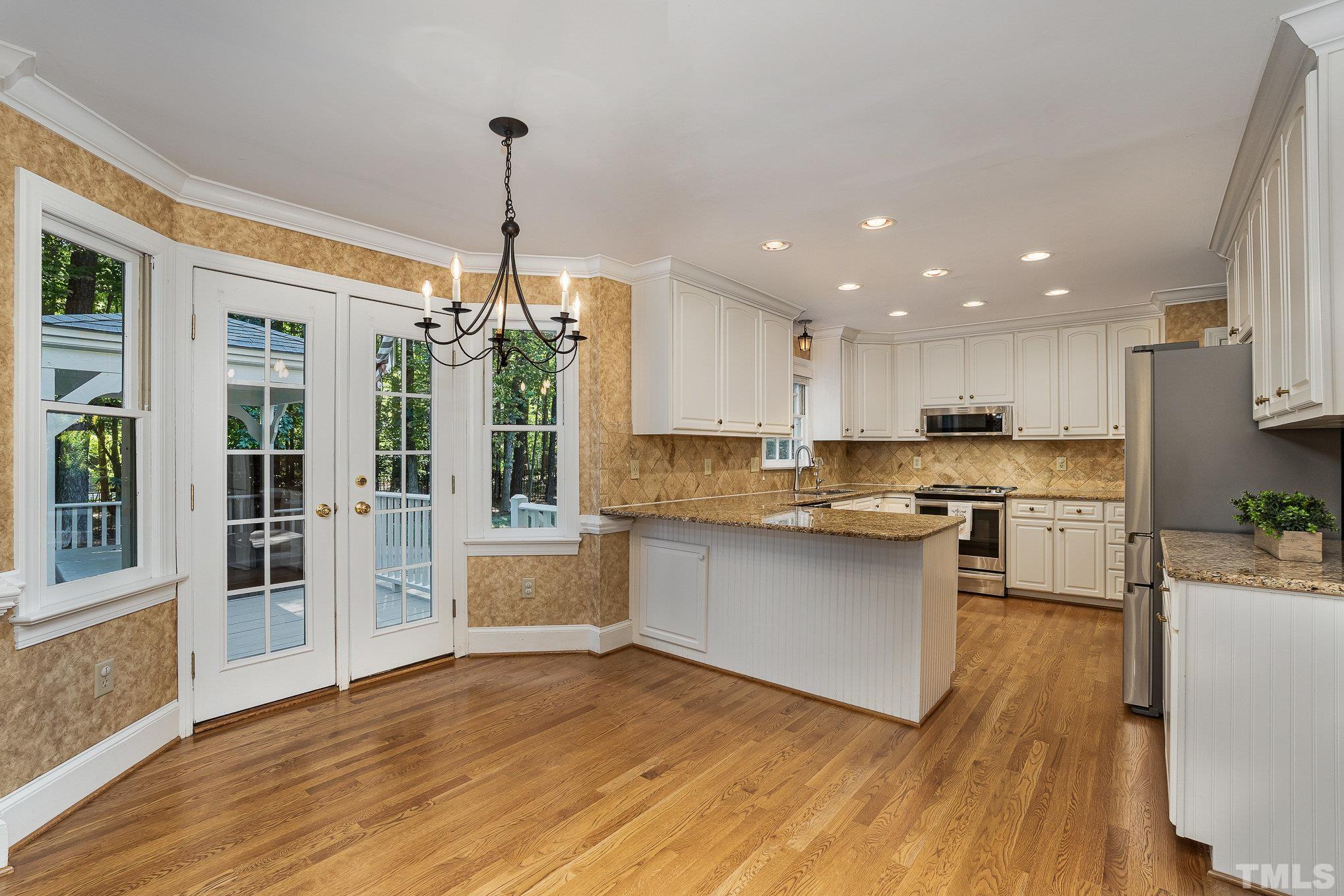 12036 Warwickshire Way Raleigh, NC 27613 - Photo 4 of 40 a kitchen with stainless steel appliances granite countertop a refrigerator a sink dishwasher a stove and white countertops with wooden floor