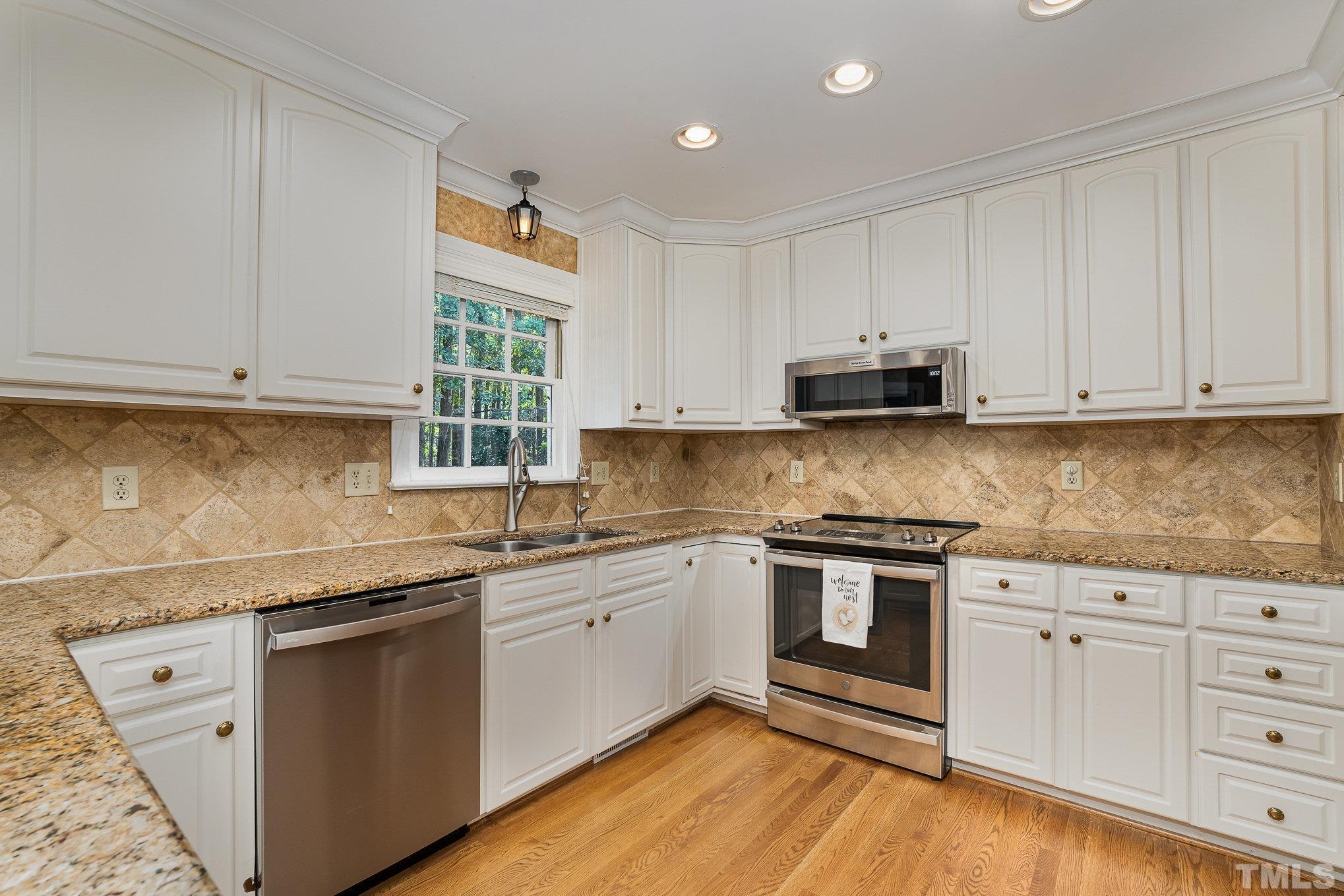 12036 Warwickshire Way Raleigh, NC 27613 - Photo 6 of 40 a kitchen with stainless steel appliances granite countertop a sink and cabinets with wooden floors