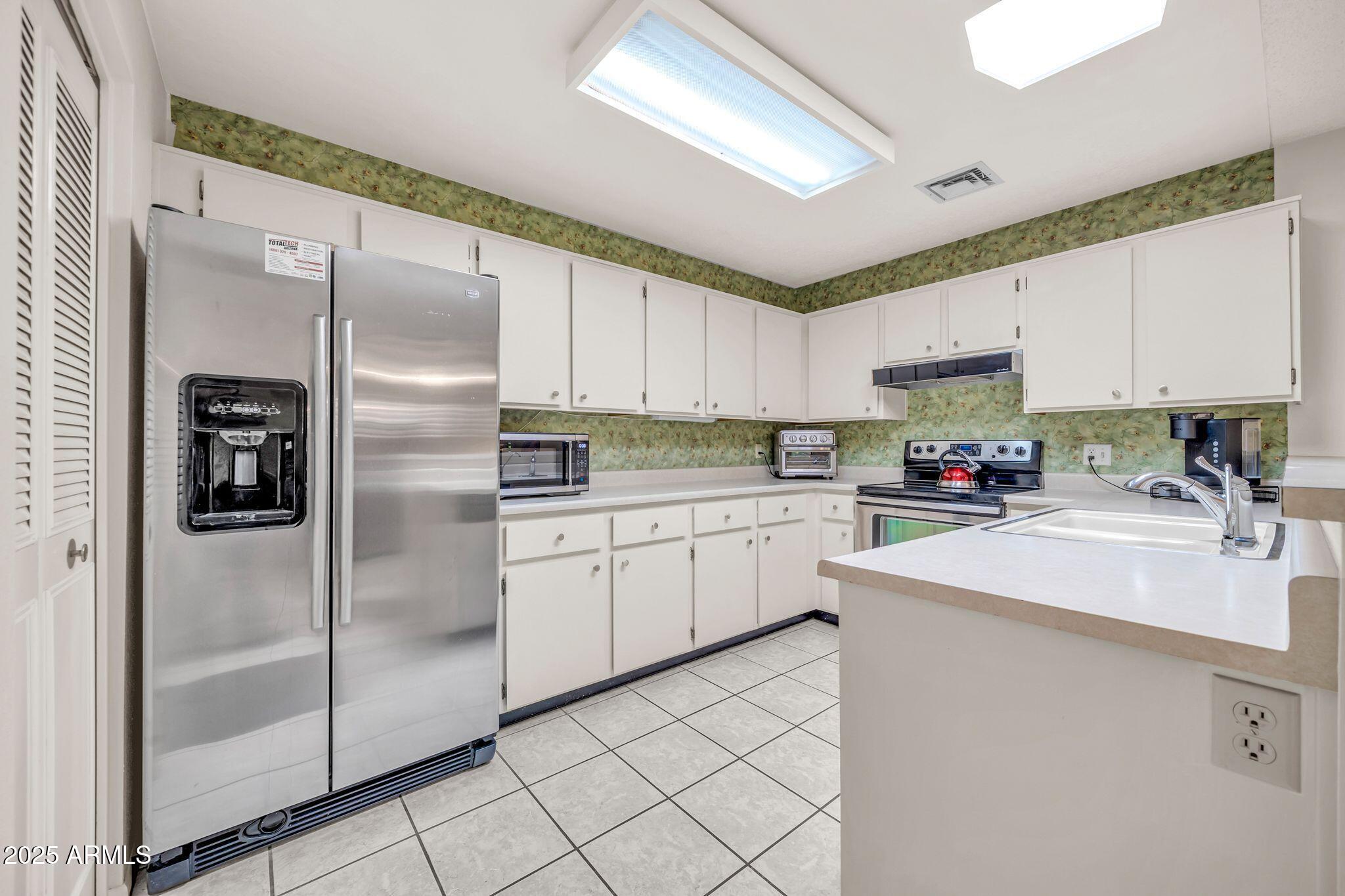 14300 West Bell Road, Unit 83 Surprise, AZ 85374 - Photo 9 of 22 a kitchen with a refrigerator a sink and cabinets