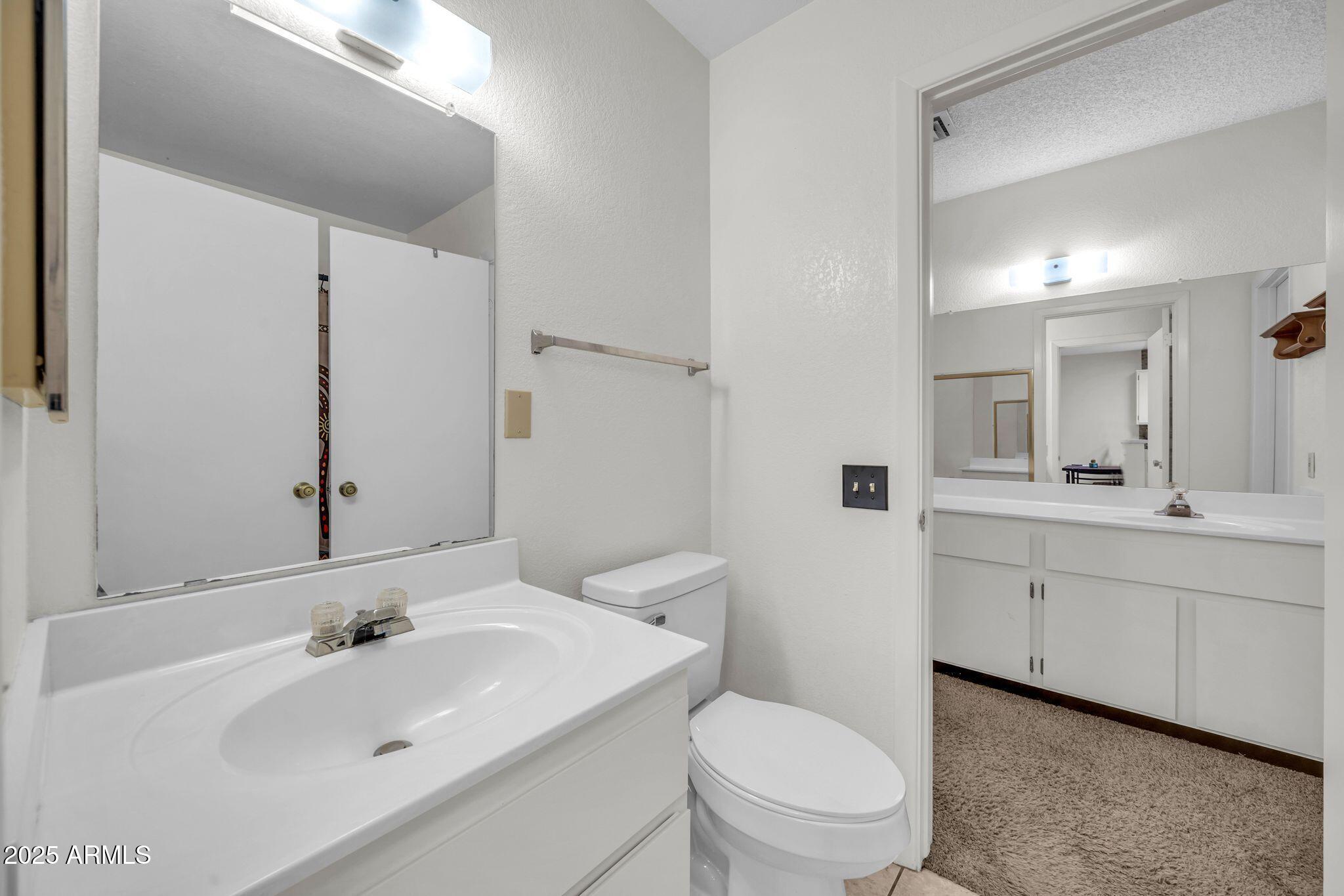 14300 West Bell Road, Unit 83 Surprise, AZ 85374 - Photo 10 of 22 a bathroom with a toilet a sink a mirror and a bathtub