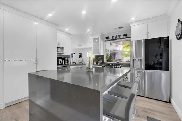 a view of a kitchen with kitchen island a counter top space a sink stainless steel appliances and cabinets
