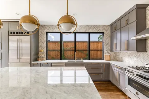 a kitchen with granite countertop a stove a sink and a large window