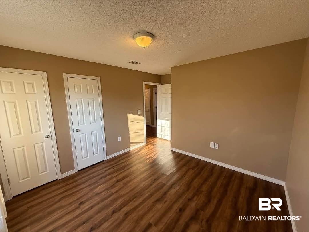 8912 Sherman Road Foley, AL 36535 - Photo 19 of 35 Unfurnished bedroom with dark wood-style floors, baseboards, visible vents, and a textured ceiling
