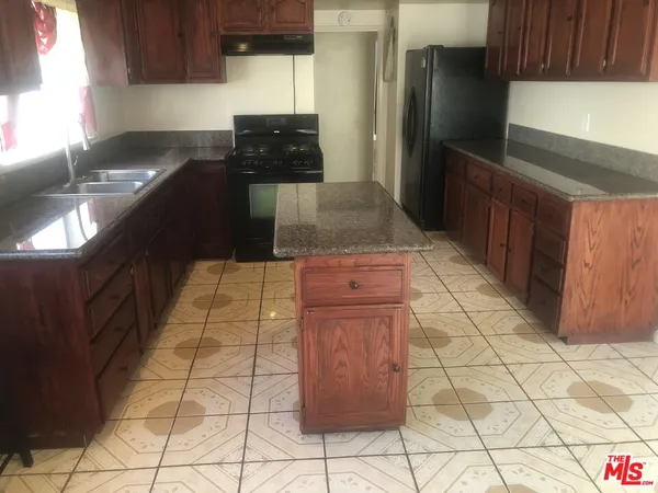 a kitchen with granite countertop a stove a refrigerator and a cabinets
