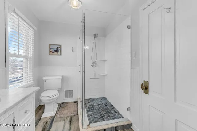 a bathroom with a sink a toilet a window and shower