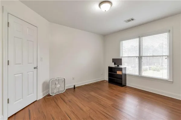 an empty room with wooden floor cabinet and windows