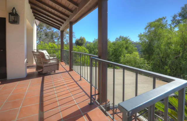 a balcony with wooden floor stairs and furniture