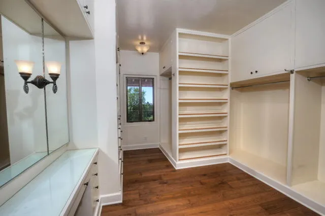 a view of an empty walk in closet and wooden floor