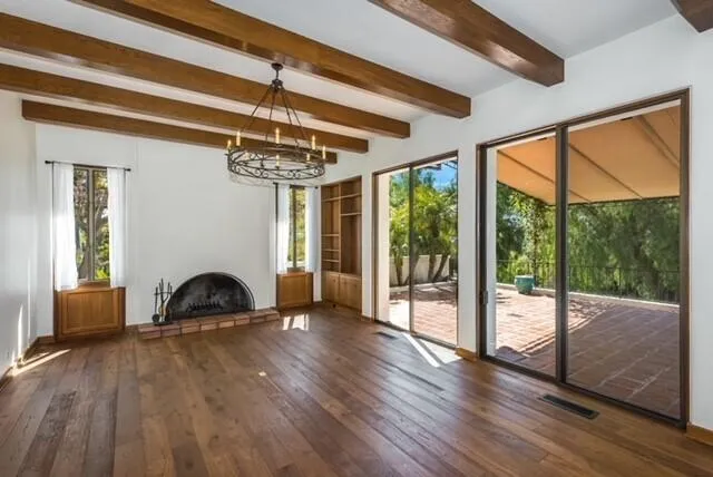a view of a livingroom with furniture wooden floor windows and a fireplace