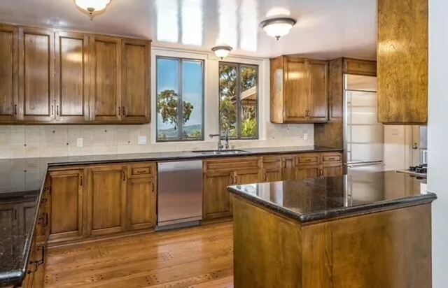 a kitchen with stainless steel appliances granite countertop a sink and a granite counter tops with wooden floors