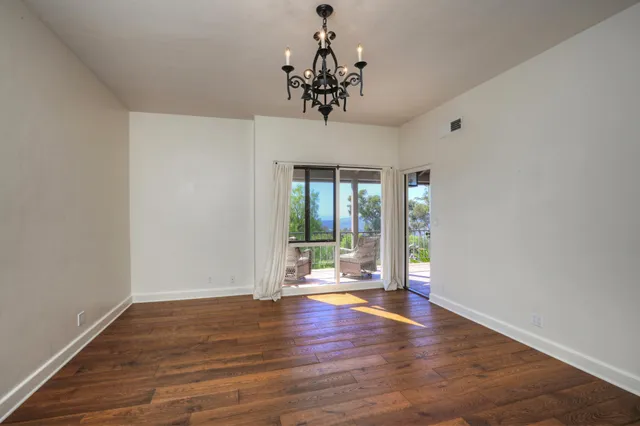 a view of a livingroom with wooden floor a chandelier and a window
