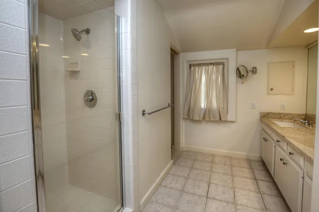 a bathroom with a granite countertop sink a mirror and a shower