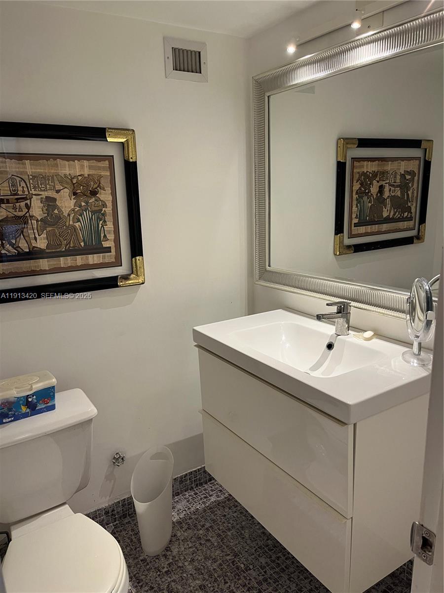 8233 Harding Avenue, Unit 305 Miami Beach, FL 33141 - Photo 23 of 39 a bathroom with a toilet a sink and mirror