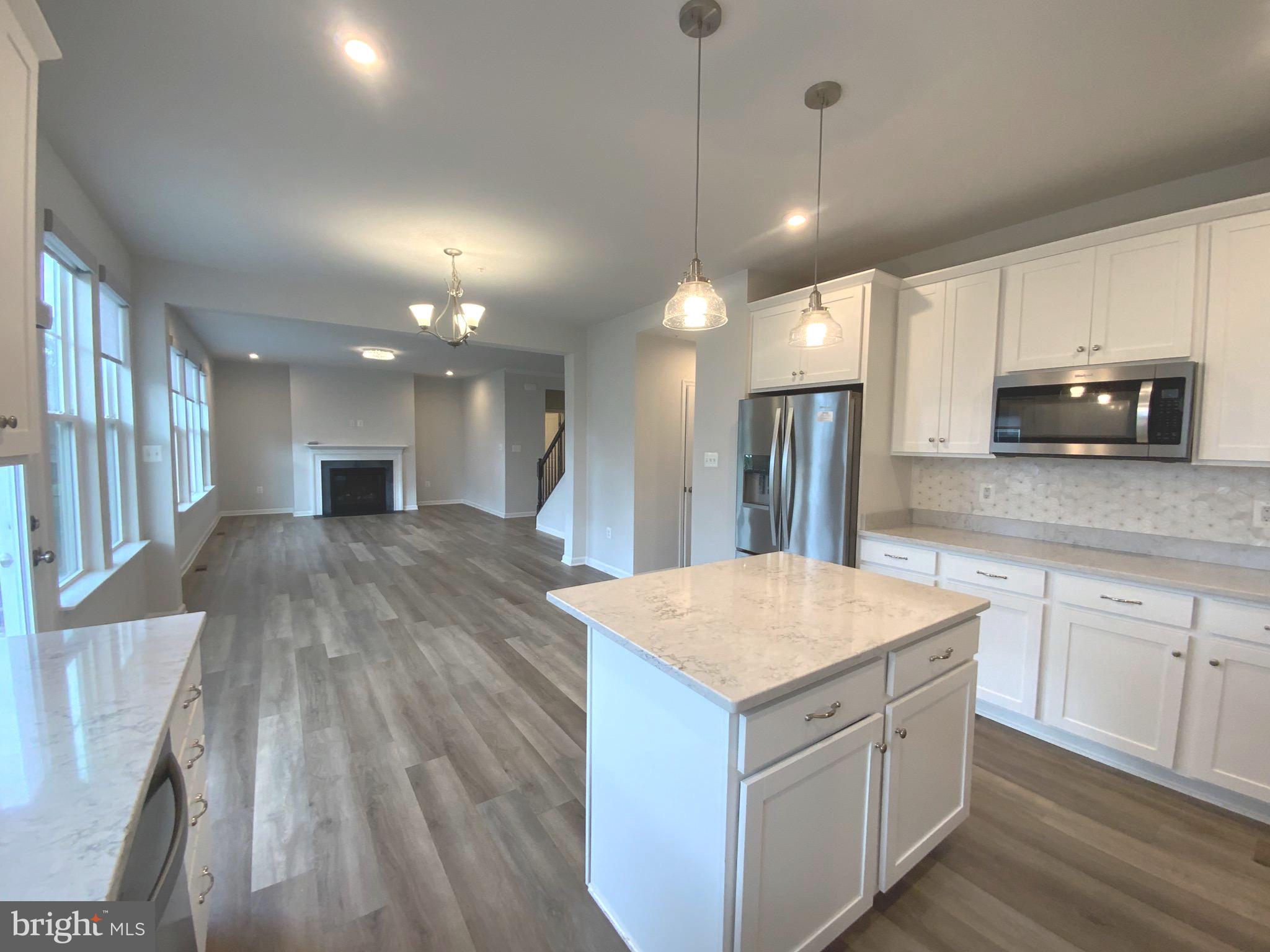 5763 Hawk Ridge Road Frederick, MD 21704 - Photo 13 of 73 a large kitchen with kitchen island a stove a sink a refrigerator and a wooden floor