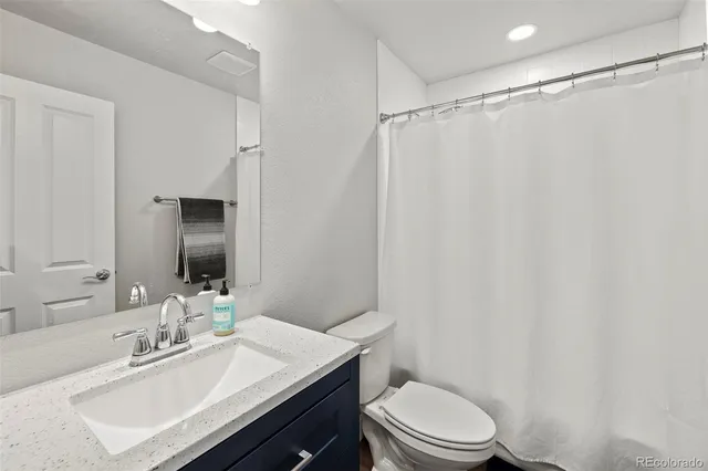 a bathroom with a sink a toilet a mirror and shower curtain