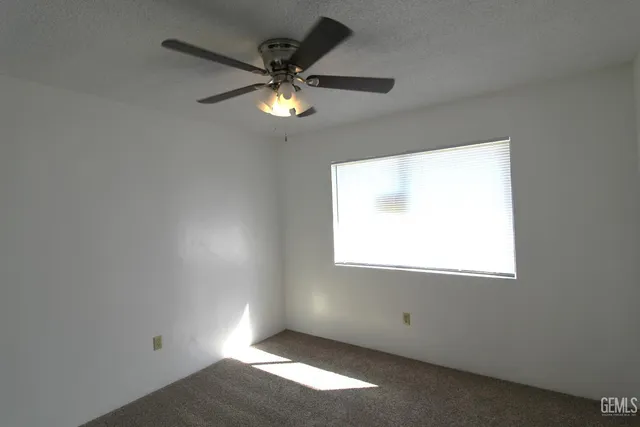 an empty room with a window and a fan