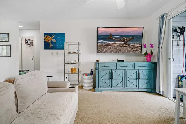 a living room with furniture a flat screen tv and wall paintings