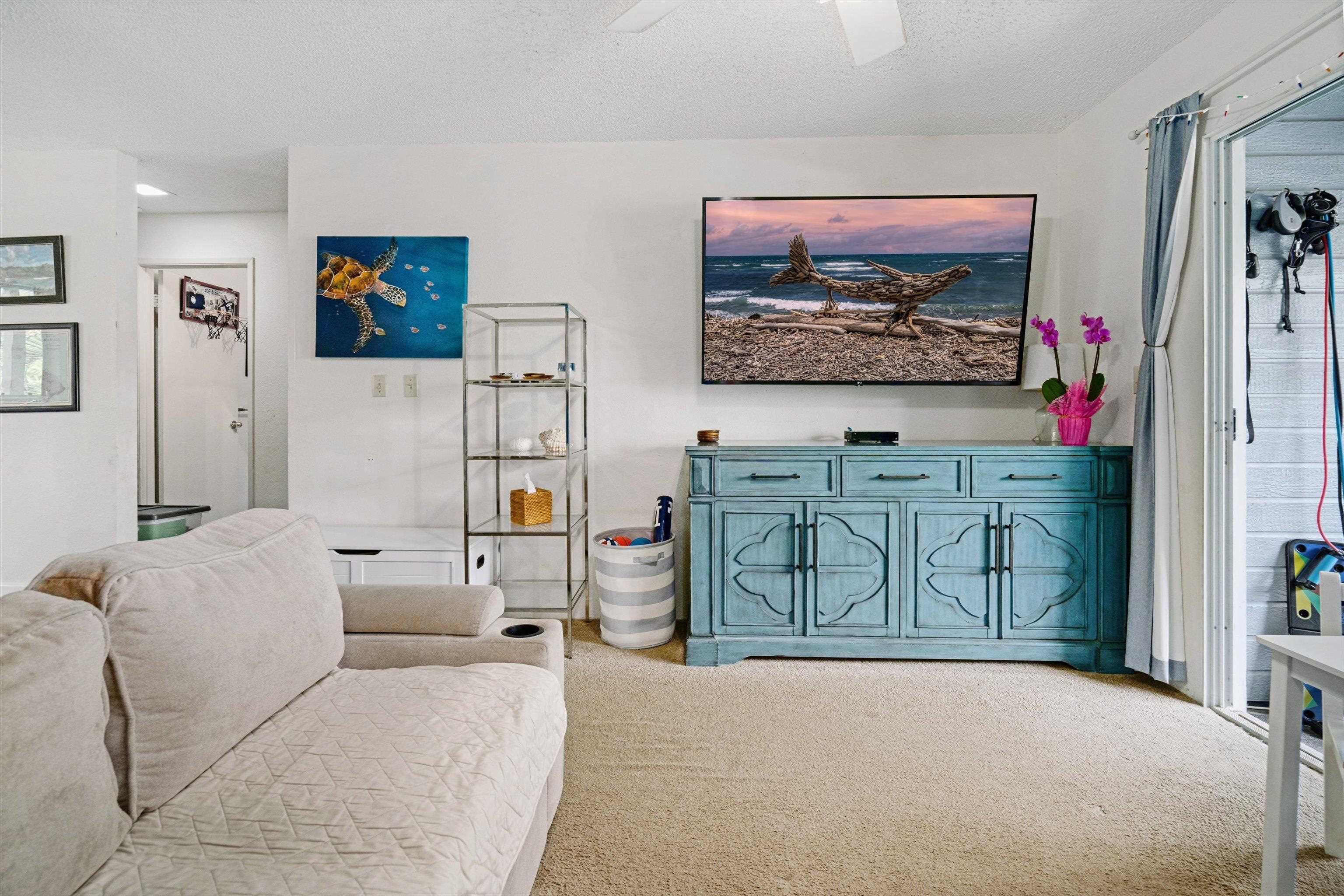 160 Keonekai Road, Unit 27201 Kihei, HI 96753 - Photo 18 of 29 a living room with furniture a flat screen tv and wall paintings