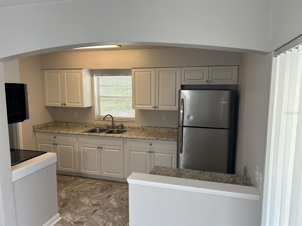 1241 Pilgrim Road Spring Hill, FL 34606 - Photo 12 of 28 a kitchen with a sink a refrigerator and cabinets