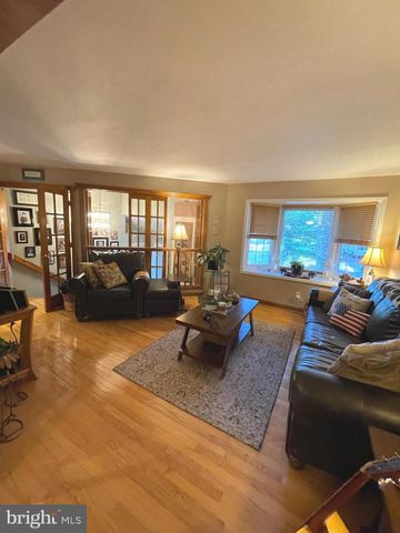 a living room with furniture hard wood floor and a floor to ceiling window