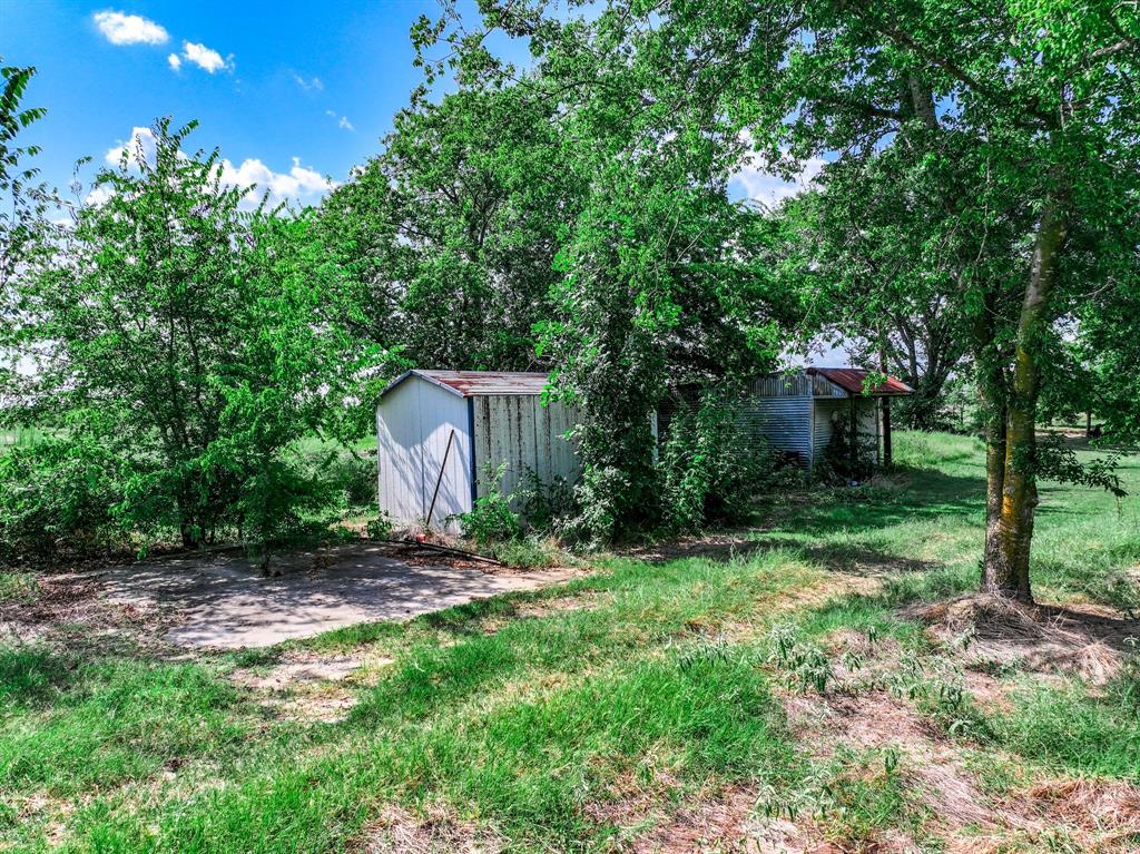 7801 West Interstate Highway Cumby, TX 75433 - Photo 17 of 32 a view of a backyard with a barn and large trees