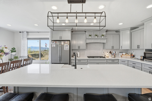 638 Canyon Rim Road Smithfield, UT 84335 - Photo 8 of 56 Kitchen featuring a breakfast bar area, gray cabinets, stainless steel appliances, light stone counters, and a mountain view