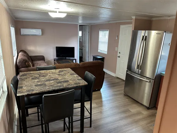 a living room with stainless steel appliances granite countertop furniture a refrigerator a stove a kitchen island with wooden floor