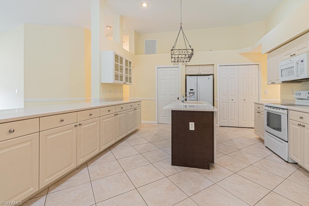 7101 Timberland Circle Naples, FL 34109 - Photo 11 of 50 a kitchen with granite countertop white cabinets and white appliances