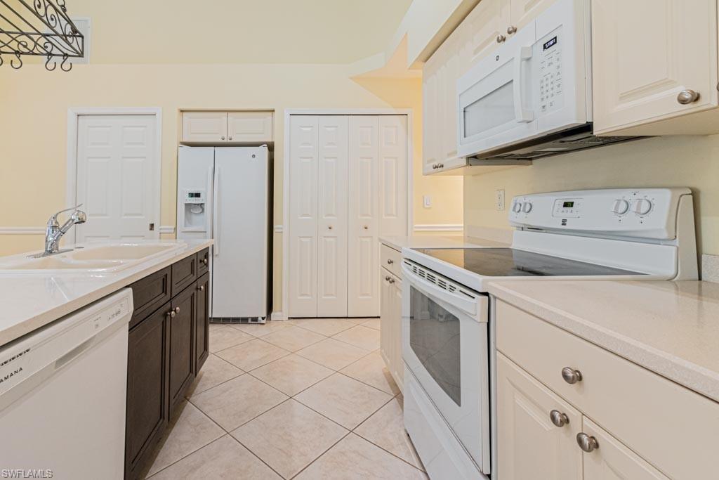 7101 Timberland Circle Naples, FL 34109 - Photo 10 of 50 a kitchen with white cabinets and white appliances