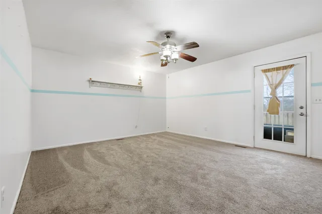 a view of an empty room with a chandelier fan