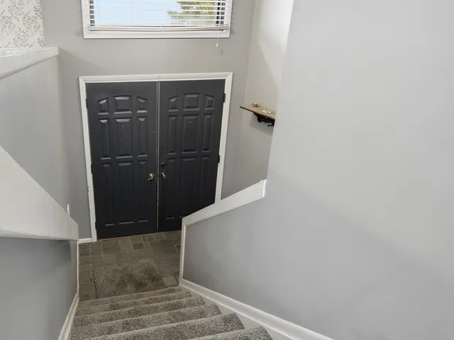 a view of an empty room with chandelier fan and fire place
